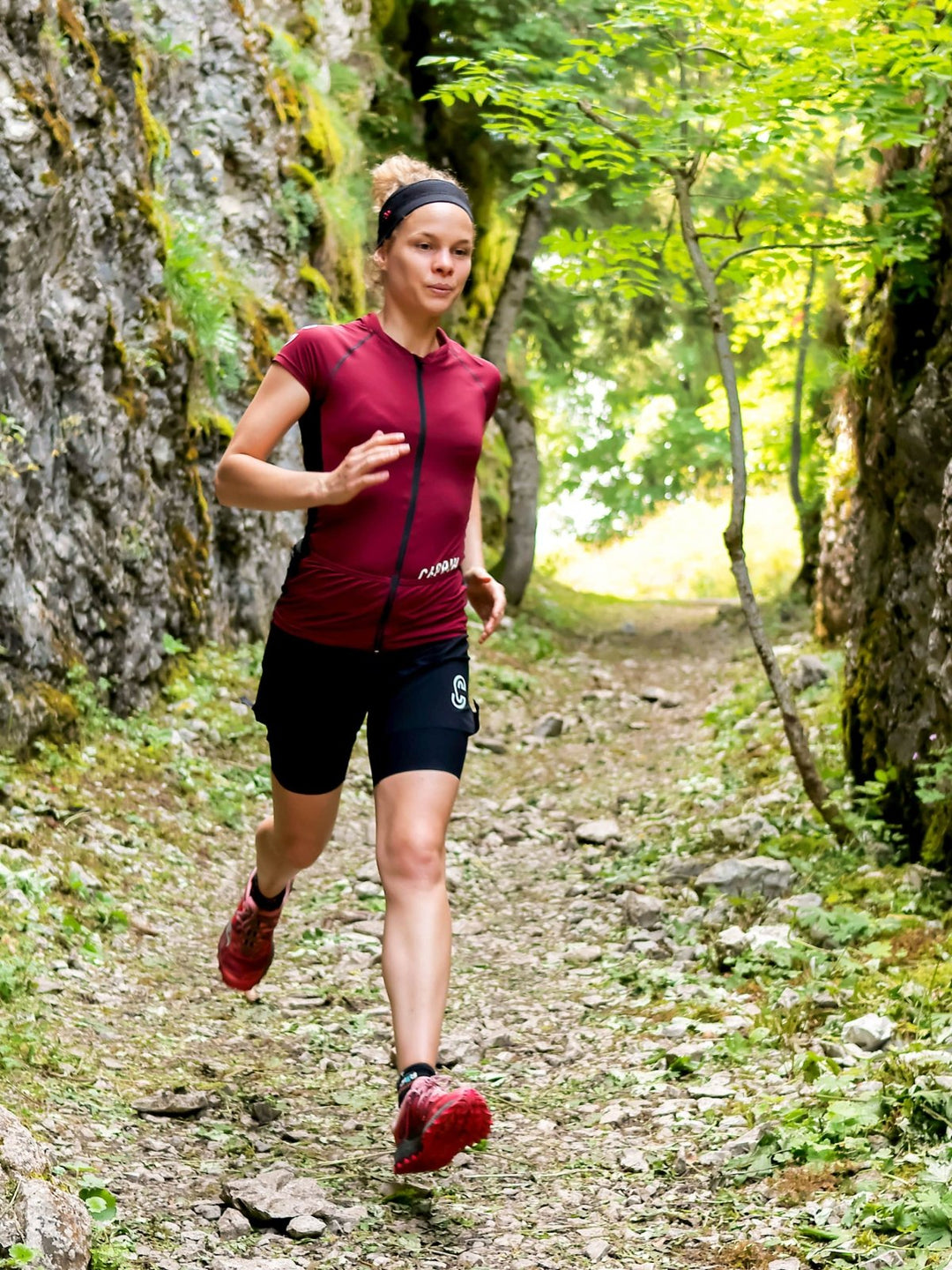 Maillot de trail Ruby porté par une femme en train de courir Caprin #couleur_ruby-wine